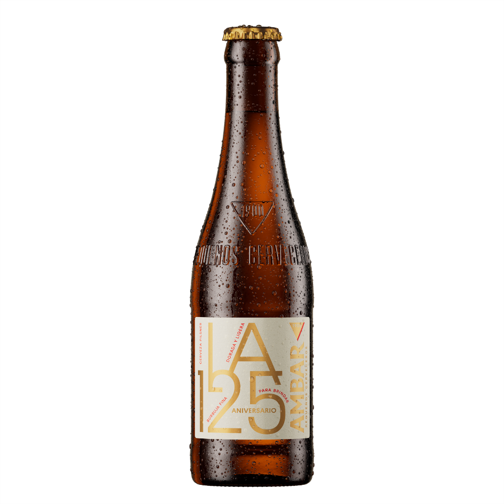 Botella de cerveza Ambar La 125 Aniversario fría, con gotas de agua sobre el cristal marrón y chapa metálica dorada. La etiqueta frontal, de fondo blanco o crema, destaca por sus tipografías en dorado con la inscripción "LA 125 ANIVERSARIO", junto con detalles en vertical como "Cerveza Pilsner" y el logotipo de Ambar. El vidrio incluye grabado en relieve el año "1900" y la frase "Pequeños Cerveceros".